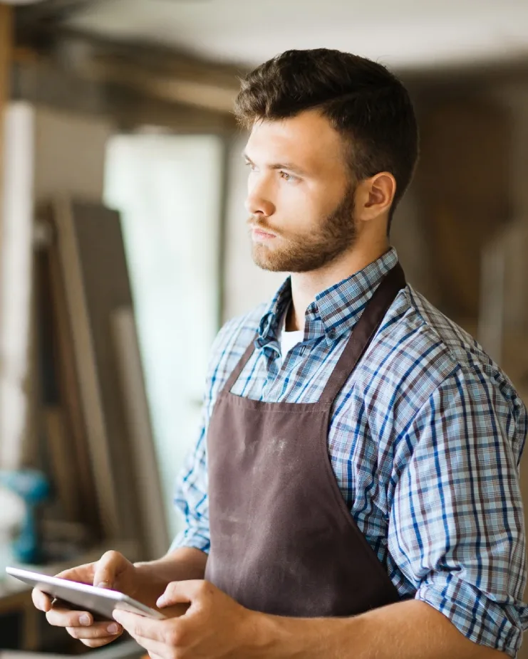 Handwerker in seiner Werkstatt mit einem Tablet in der Hand