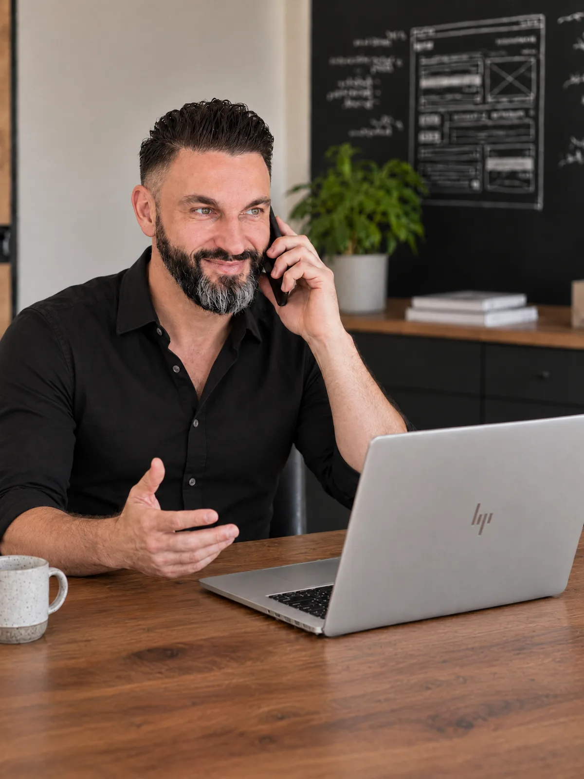 Dirk Meißner, Webdesigner aus Wilsdruff, telefoniert am Holztisch vor seinem Laptop
