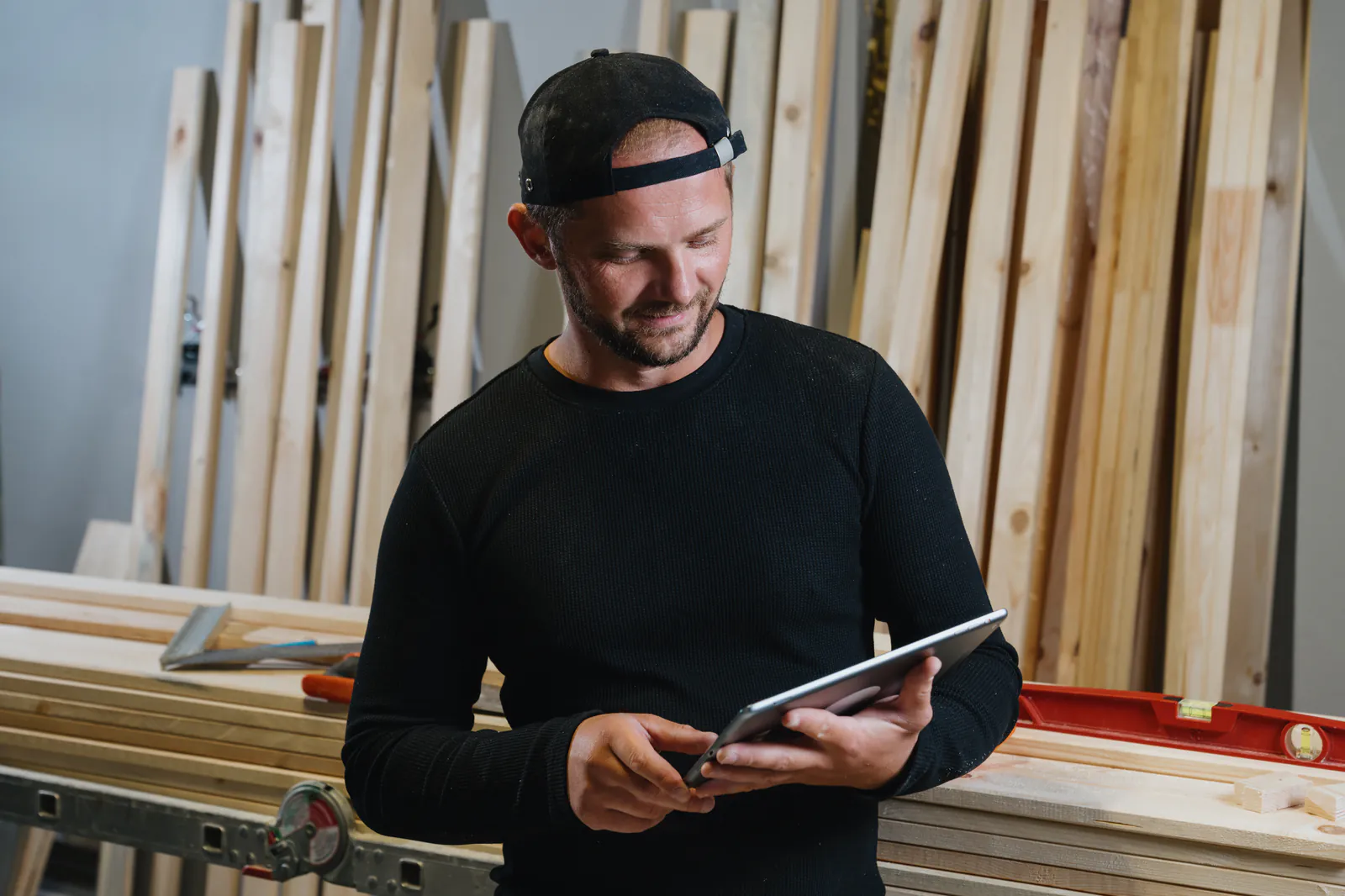 Tischler schaut in seiner Werkstatt auf ein Tablet
